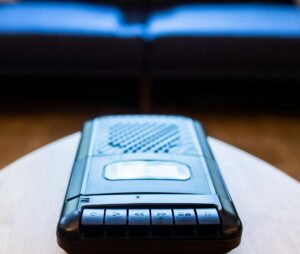 A voice recorder set on a table in front of a blue sofa.